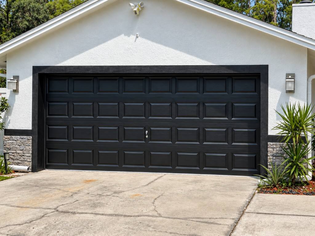 Modern black garage door on a white stucco home